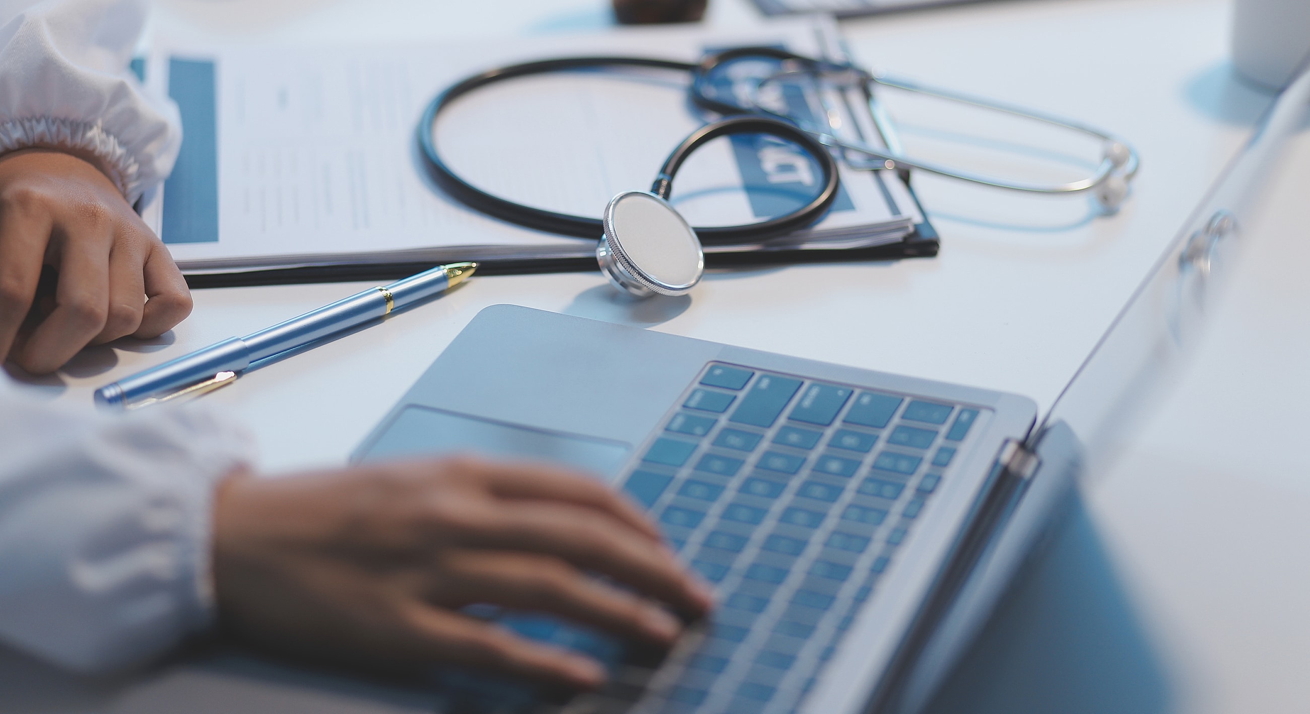 Medical professional working on a laptop desk.