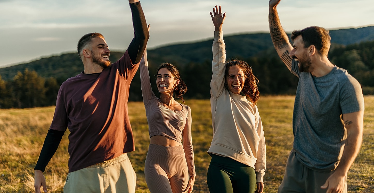 Group of friends celebrating outdoors with raised hands.