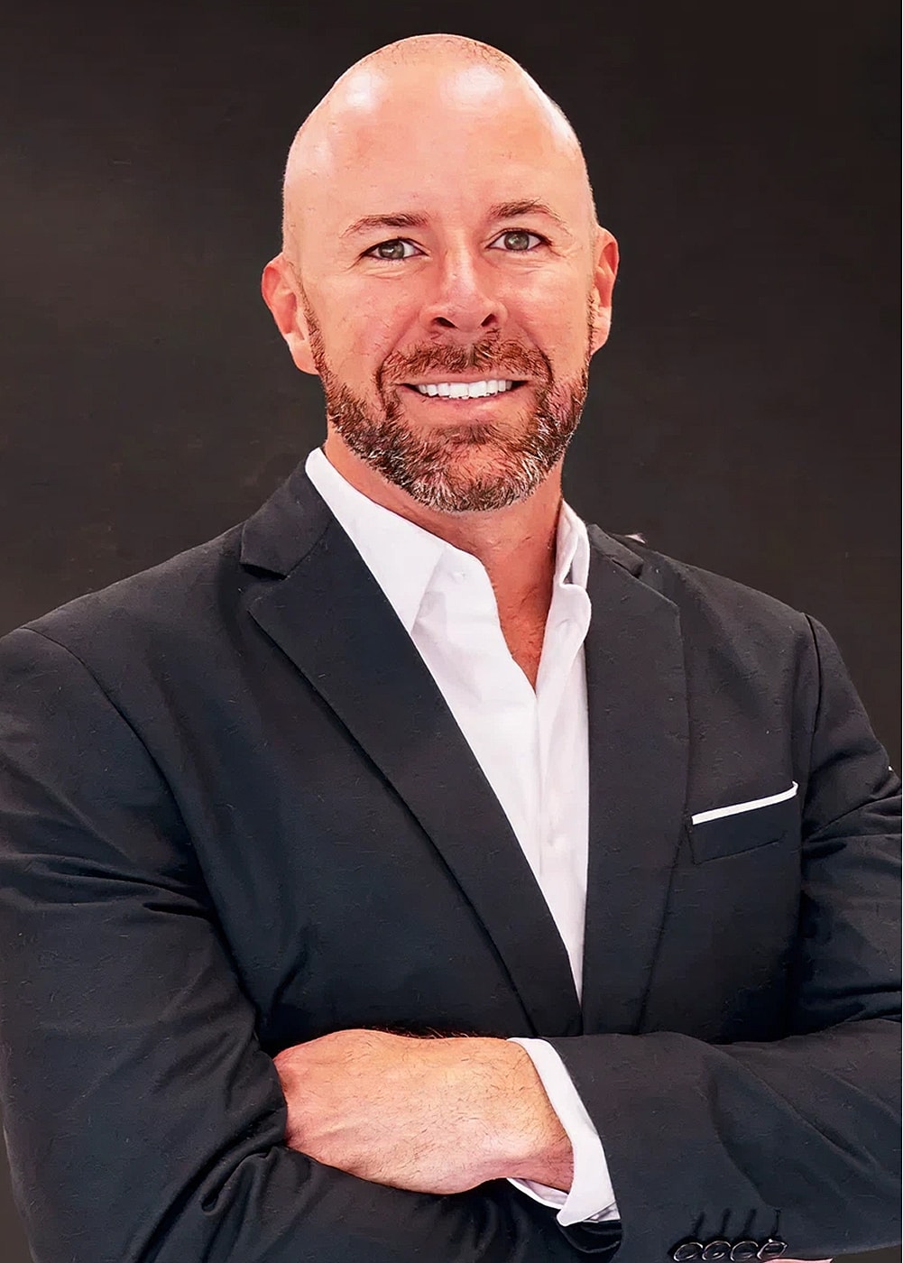 Smiling man in a suit with crossed arms.